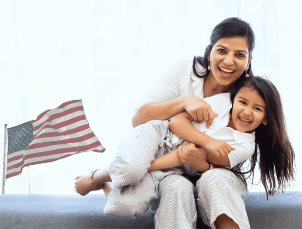 This image reflects the happiness an investor family experiences in the US   especially after they have secured the Green Card for all the eligible family members, or after they have applied for citizenship.  EB 5 visas are the choicest path for many investors to realize their plan of settling in the US and providing their families the advantage of the US education system as well as global American society.  In the backdrop of the American Flag the image projects a mother and a daughter expressing their happiness in America.